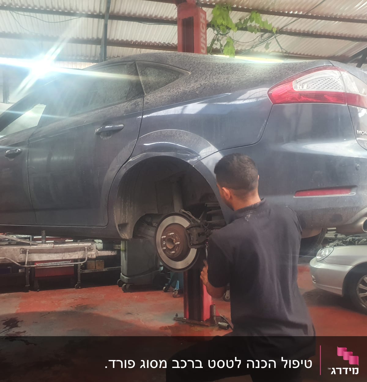 מכונאי עובד על רכב מורם במוסך